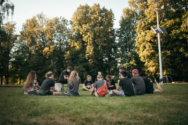 Young people sit in a circle on grass