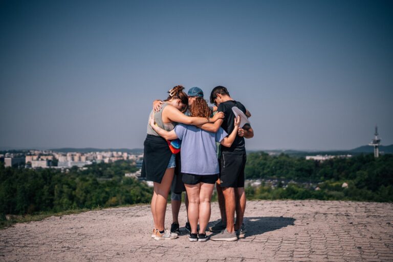 A group of young people in a circle put their arms around each other